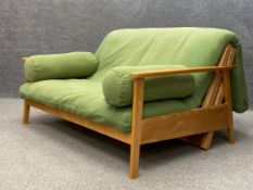A contemporary two seater Haiku sofa bed by Futon Company having birch frame with a lime green