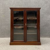 A 19th century dwarf bookcase having a moulded cornice over two glazed doors opening on to an