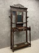 A 19th century oak hall stand having a shaped and carved pediment above a rectangular mirror with