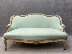 A French 19th century Louis XV style walnut settee having a carved and shaped top rail over a