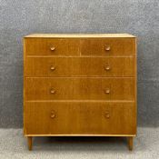 A mid century oak chest of four long graduating drawers with turned handles raised on straight