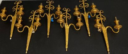 A set of six Regency style gilt metal two branch wall sconces each having a scrolling ribbon and bow