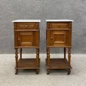 A pair of early 20th century French oak bedside cabinets each having a square white marble top