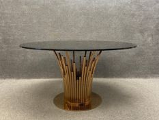 A contemporary Italian Mauris dining table having a circular black tempered glass top raised on a