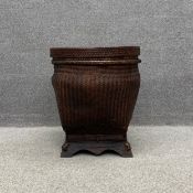 An early 20th century Chinese hand woven rattan lidded basket of square bombe form raised on a