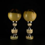 A pair of 20th century Art Deco style table lamps each having a moulded spherical amber glass