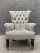 A 19th century button back library armchair having a tapered back with scrolling arms over a