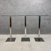 A set of three contemporary Libra bar tables each having a square plate glass top raised on a