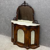 A 19th century walnut credenza having an arched mirror back with a distressed plate and carved