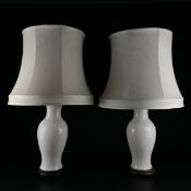 A pair of contemporary Chinese white porcelain table lamps of baluster vase form raised on footed