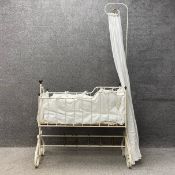 A Victorian white painted cast iron cot with a swinging action having a tall scrolled stem with a