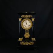 An early 19th century French Empire style ebonised and ormolu mounted striking portico mantle clock,