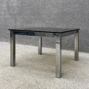 A mid to late 20th century coffee table having a square smoked glass top raised on a square polished