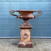 A Victorian cast iron urn having a wide flared rim over a shaped and reeded body with scrolling twin