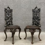 A pair of heavy Victorian style cast iron garden chairs each having an arched top rail above a