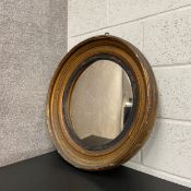 A Regency circular mirror having a convex plate in an ebonised slip border within a giltwood