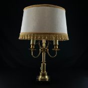 A 20th century brass Empire style lamp having a tasseled shade over three branches terminating in