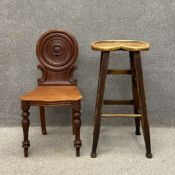 A mid 19th century mahogany hall chair having a circular carved back with scrolling decoration