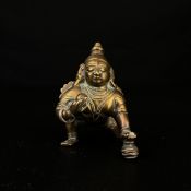 A 19th century Indian school cast brass figure of a crawling Krishna. H.8cm