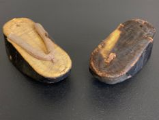 A pair of traditional Chinese clogs each having a rolled canvas strap on a tightly woven straw