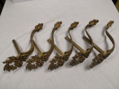 A set of four gilt metal Rococo wall brackets each having a foliate plume cresting over a shaped
