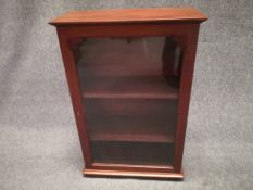 A small mahogany cabinet having a moulded cornice above a single glazed door opening on to a