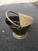 A 19th century brass helmet coal scuttle with a swing handle and repousse decoration along with a