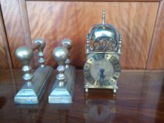 A collection of brass to include a lantern clock and a pair of early 20th century brass fire dogs.
