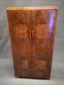 A mid 20th century Art Deco style small walnut wardrobe having a shaped and moulded top above two