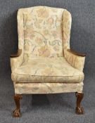 A mid Georgian style wing armchair in tapestry upholstery raised on carved cabriole ball and claw