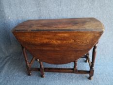A mid century oak drop leaf dining table having an oval thumb moulded top raised on turned and