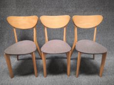 A set of three mid century style beech chairs each having a curved and shaped back over a lozenge