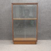 A mid-century teak and glass display cabinet with a single shelf on a pedestal base. H.154 W.93 D.