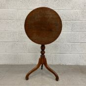 A 19th century oak occasional table having a circular top with a tilt action raised on a turned
