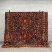 A 19th century Persian Kamseh carpet having three central diamond lozenge medallions in iron red