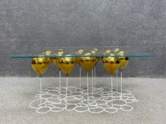 A contemporary UP Ballon table having a rectangular toughened glass top raised on a cluster of
