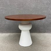 A contemporary Maia style dining table having a circular teak top raised on a conical plinth base