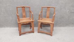 A pair of 20th century Chinese hardwood armchairs each having a curved top rail and arms with a