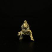A small 19th century cast brass figural model of a crawling Krishna. H.4.5cm