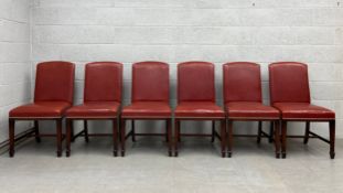 A set of six 20th century dining chairs each having a red leather upholstered back and stuffover
