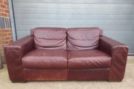 A contemporary Italian maroon leather two seater sofa having a square cushioned back arms and seat