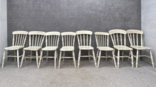 A matched set of eight white painted pine farmhouse style spindle back dining chairs each having a