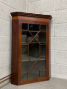 A Georgian wall mounted corner cabinet having a dentil moulded cornice with a crossbanded