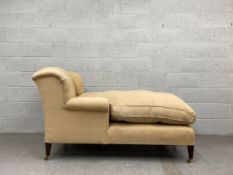 A 20th century chaise longue or day bed having a wing back and scrolled arms over a long cushioned