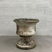 A large reconstituted stone urn or garden planter having an egg and dart moulded rim over a semi