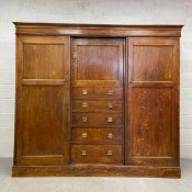 A 19th century oak compactum wardrobe having a moulded cornice over a small central panelled cabinet