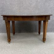 An Edwardian mahogany extending dining table having an oval top over a crossbanded frieze raised