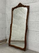 A 19th century French oak pier mirror having an ornately carved and shaped frame with a scrolling