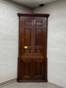 A Georgian oak corner cabinet having a moulded cornice over two long panelled cabinet doors above