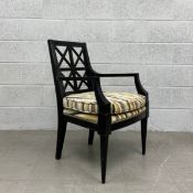 A 20th century black lacquered armchair having a square back with a geometric openwork splat with